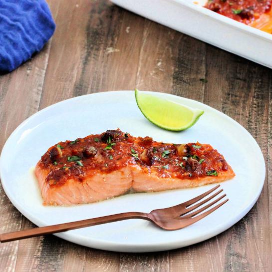 Salmon filet on white plate with harissa sauce and California dates