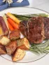 A plate with lamb chops, potatoes, and spring vegetables.