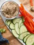 Snack platter with black bean dip, sliced cucumbers, and red bell peppers.