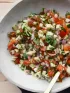 Fresh salsa with diced tomatoes, zucchini, onions, and herbs in a white bowl, with lime.