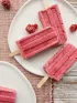 pink raspberry popsicles on white plates with scattered berries.