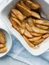 Baked apple slices with cinnamon in a white baking dish and bowl.