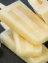 Banana popsicles stacked with banana slices on a dark background.