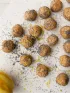 Lemon poppy seed energy bites on parchment paper with a fresh lemon.