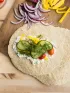 Healthy wrap with creamy spread, cucumbers, tomatoes, yellow peppers, and fresh dill.