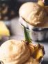 Scoops of light yellow pineapple frozen dessert garnished with fresh pineapple pieces.