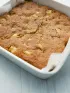 Golden-brown apple cake in a white baking dish.