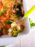 Cheesy broccoli and ham casserole in a white dish, with a serving fork.