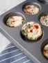 Healthy egg bites with red pepper and greens in a muffin tin.