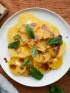 Fresh sliced oranges with mint and drizzle on a white plate. Spices nearby.