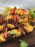 Grilled chicken and vegetable skewers with bell peppers and onions on a wooden board.