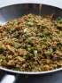 Cauliflower fried rice with vegetables and green onions in a large silver pan.