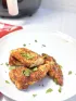 Seasoned chicken tenders with fresh parsley on a white plate.