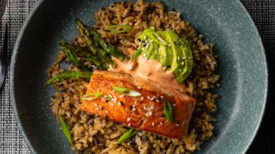 air fryer salmon with yum yum sauce on bed of rice, asparagus, and avocaco slices