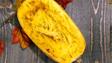 A sliced spaghetti squash on wood background representing a low carb alternative to spaghetti for diabetes friendly meal