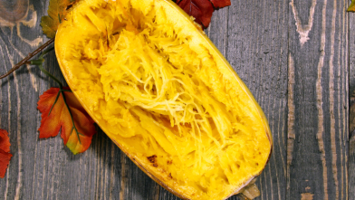 A sliced spaghetti squash on wood background representing a low carb alternative to spaghetti for diabetes friendly meal