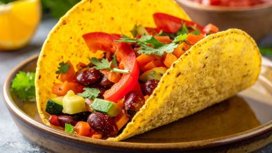 A corn tortilla taco filled with vegetables on a plate. 