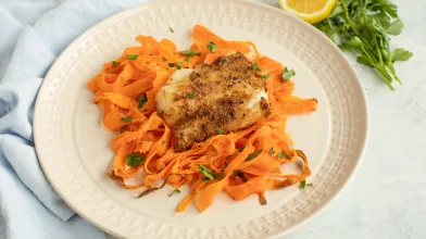 Lemon herb crusted fish with carrot ribbons on plate