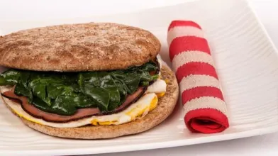 sandwich with spinach and folded striped towel on a plate