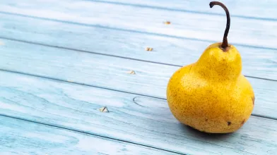 Single yellow pear on blue table