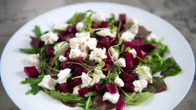 Beet and arugula salad with feta cheese in white bowl