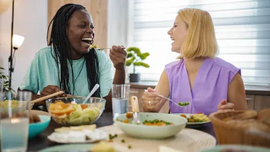 Smiling women at table eating healthy food