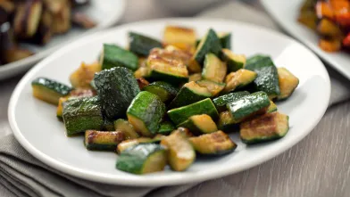 Cubes of roasted zucchini on a white plate