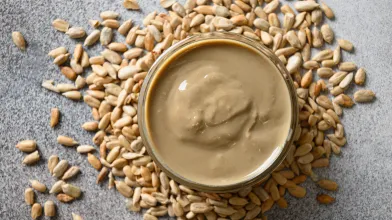 Sunflower seed butter in jar surrounded by sunflower seeds
