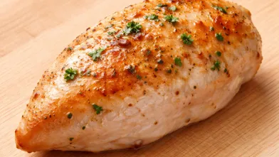 2 ounce piece of cooked chicken breast on wood cutting board