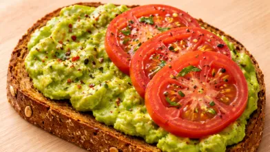 Avocado spread on whole grain toast with 3 tomato slices