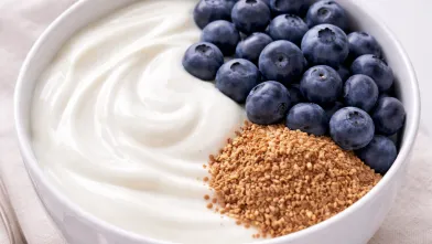 White bowl with plain yogurt, flax seeds, and fresh blueberries