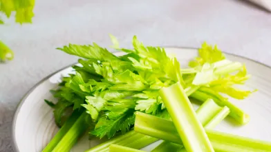Fresh chopped celery stalks and leaves on a white plate.