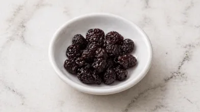 2 Tbsp of unsweetened dried cherries in a small white bowl on a marble surface. 
