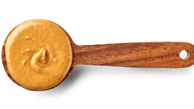 Creamy peanut butter in a wooden spoon.