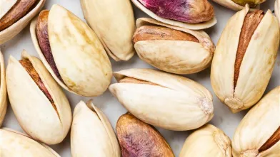 Pistachios, some shelled, on a flat surface