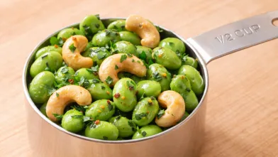 edamame and cashews with lemon and herbs in a 1/2 cup measuring cup
