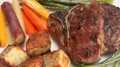 A plate with lamb chops, potatoes, and spring vegetables.