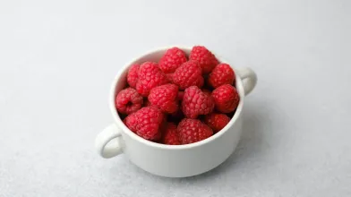 Fresh red raspberries in a white bowl.