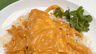 Tilapia in red curry sauce served with brown rice and a garnish of cilantro