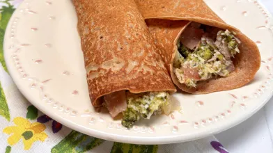  A plate of two savory crepes filled with vegetables.