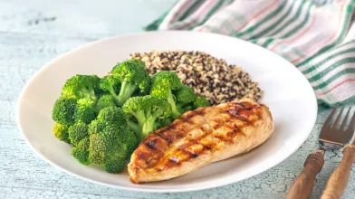 Grilled chicken, broccoli, and quinoa on a white plate.