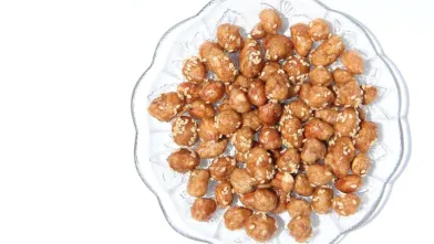 Spiced peanuts with sesame seeds on a clear glass plate.