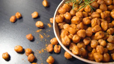 Roasted chickpeas in a bowl on a dark table.