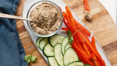 Snack platter with black bean dip, sliced cucumbers, and red bell peppers.