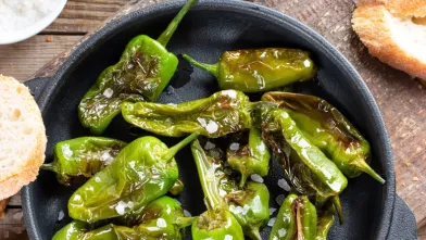 Blistered green peppers with sea salt in a black pan