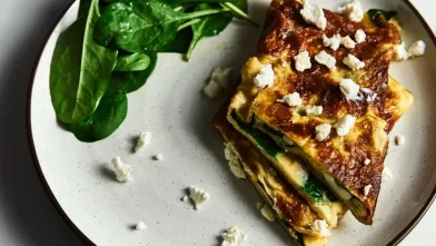 Spinach and feta omelet with fresh spinach on a white plate.