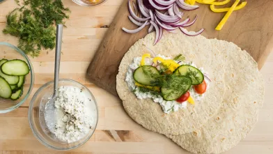 Healthy wrap with creamy spread, cucumbers, tomatoes, yellow peppers, and fresh dill.