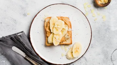Peanut butter and banana toast on a white plate.
