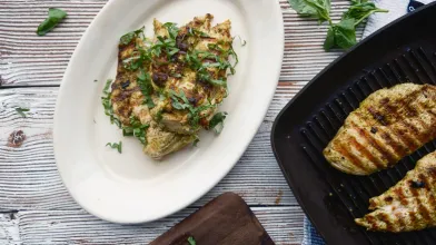 Healthy grilled chicken breasts with fresh herbs on a plate.