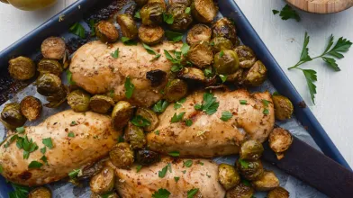 Roasted chicken breasts and Brussels sprouts on a sheet pan.